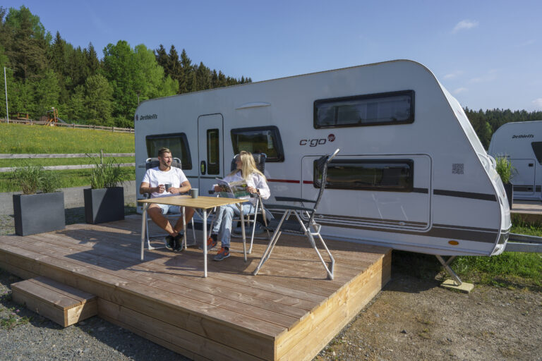 zwei Personen sitzen an einem Tisch vor einem Wohnmobil